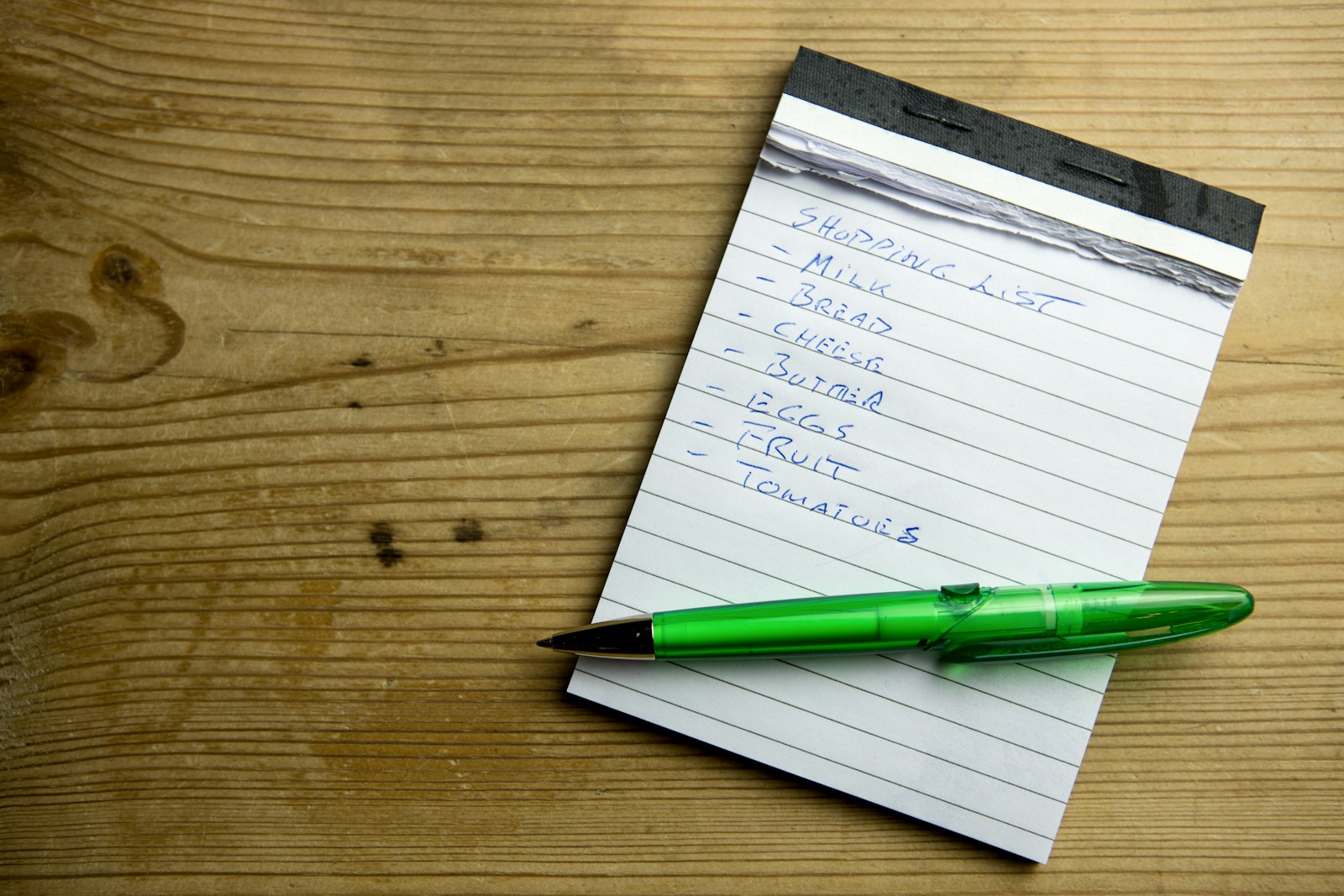 a notepad with a green pen resting on top of it