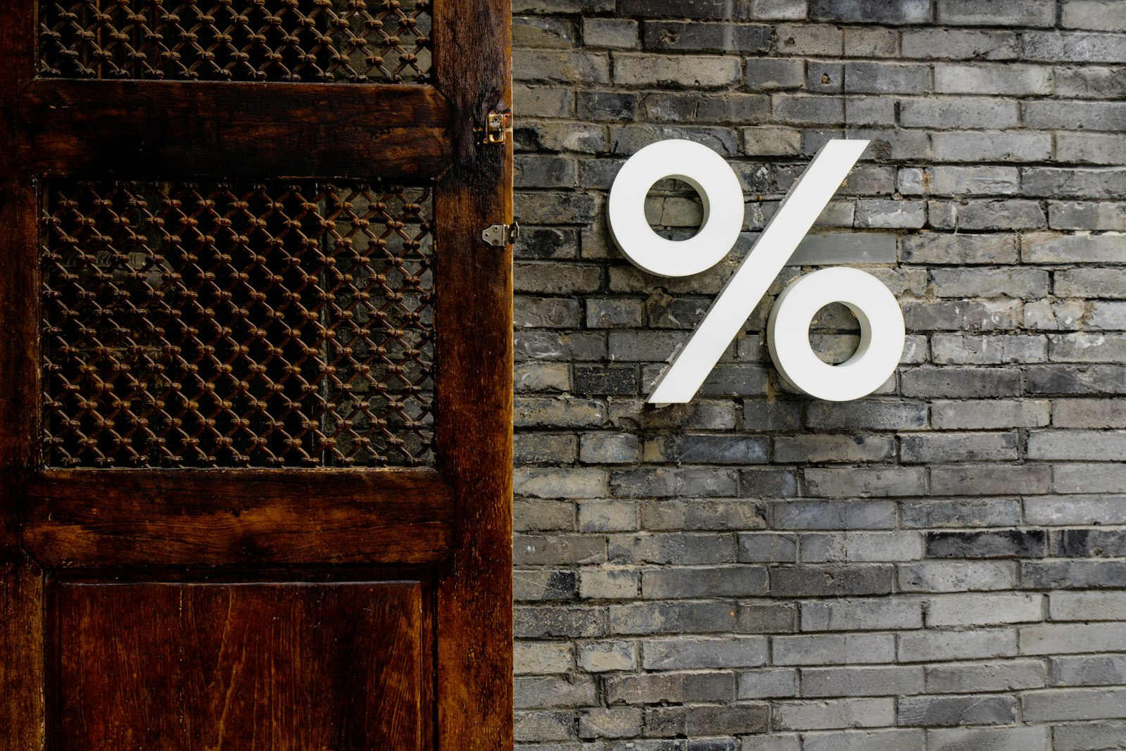 a white percentage sign painted on a brick wall