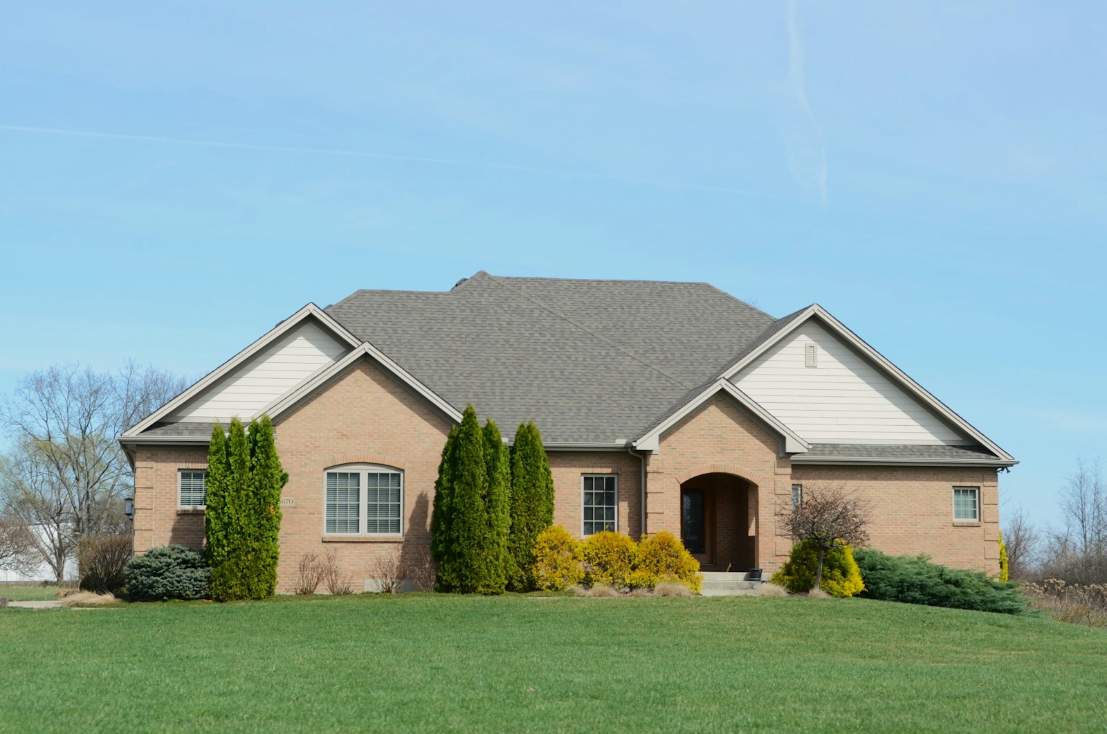a suburban brick house with a well-kept lawn
