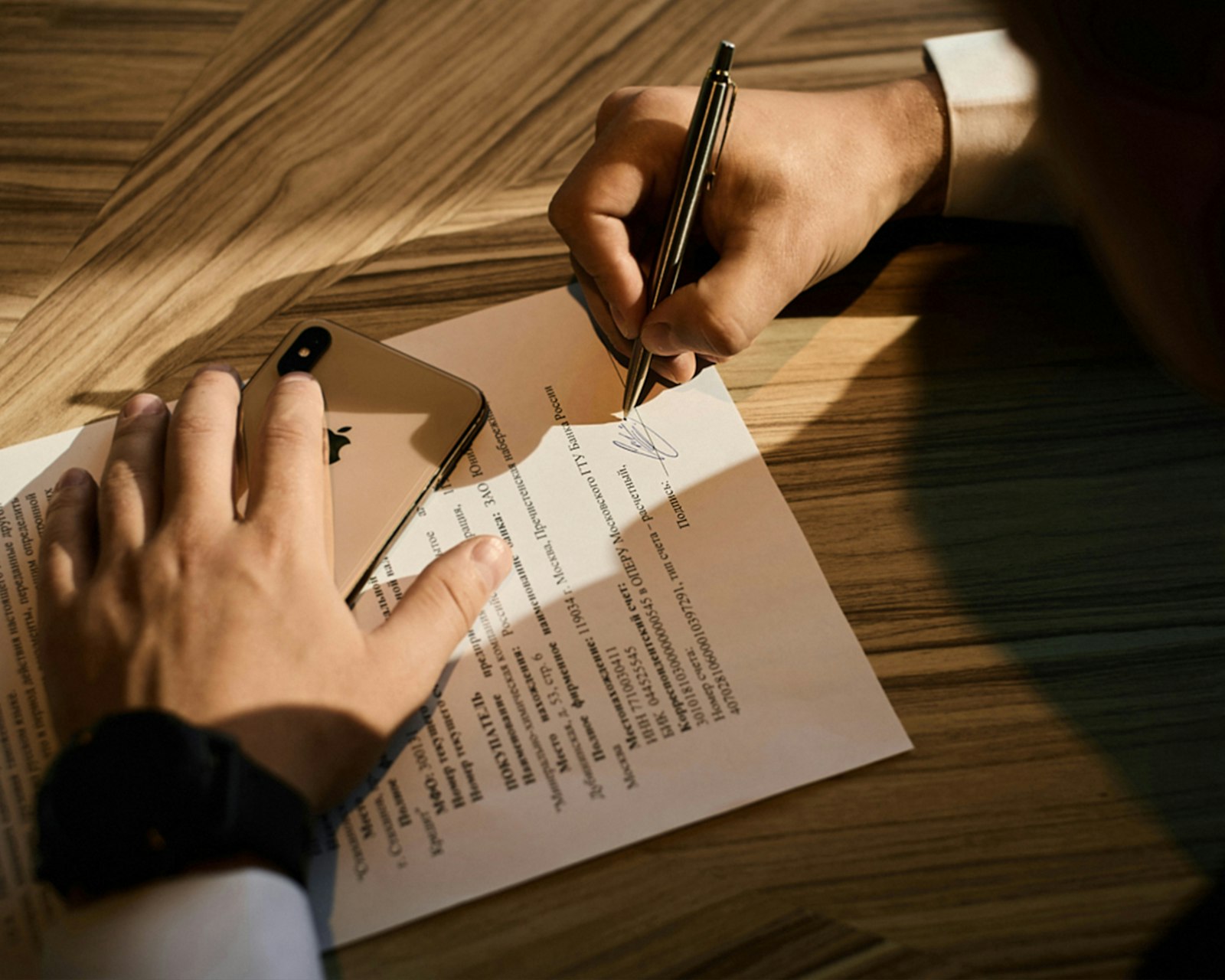 a person writing on white paper with a pen