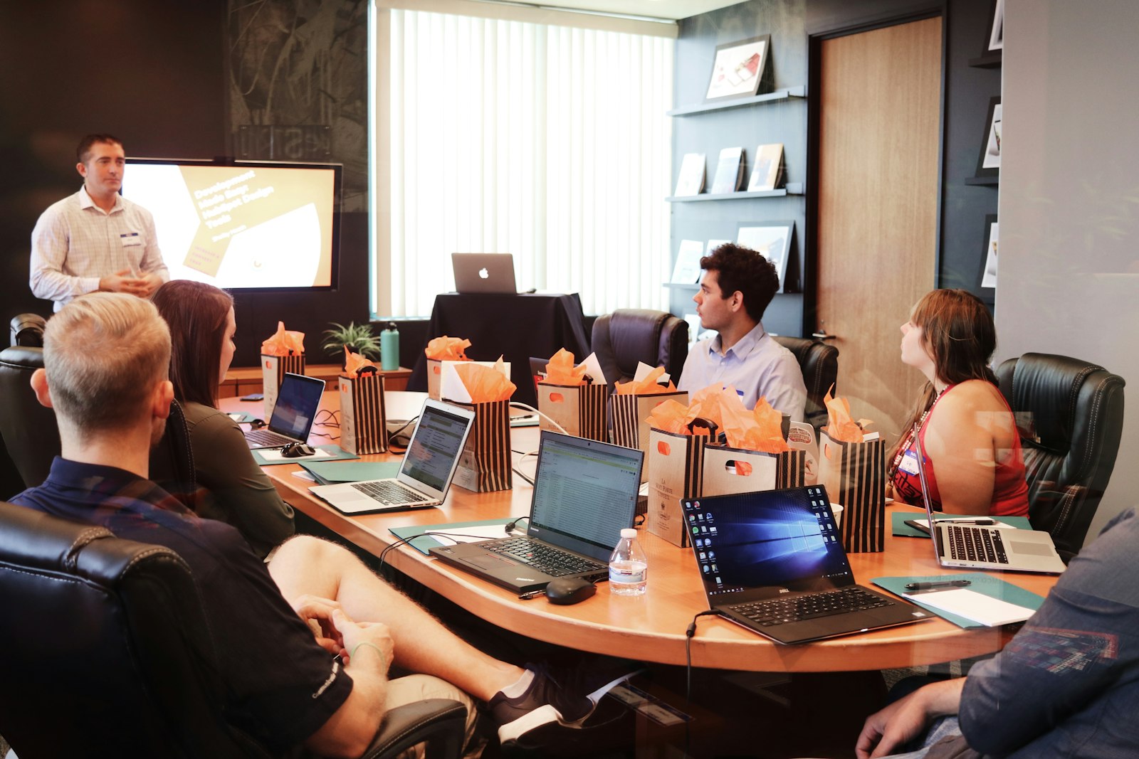 a man standing in front of people sitting beside a table with laptop computers