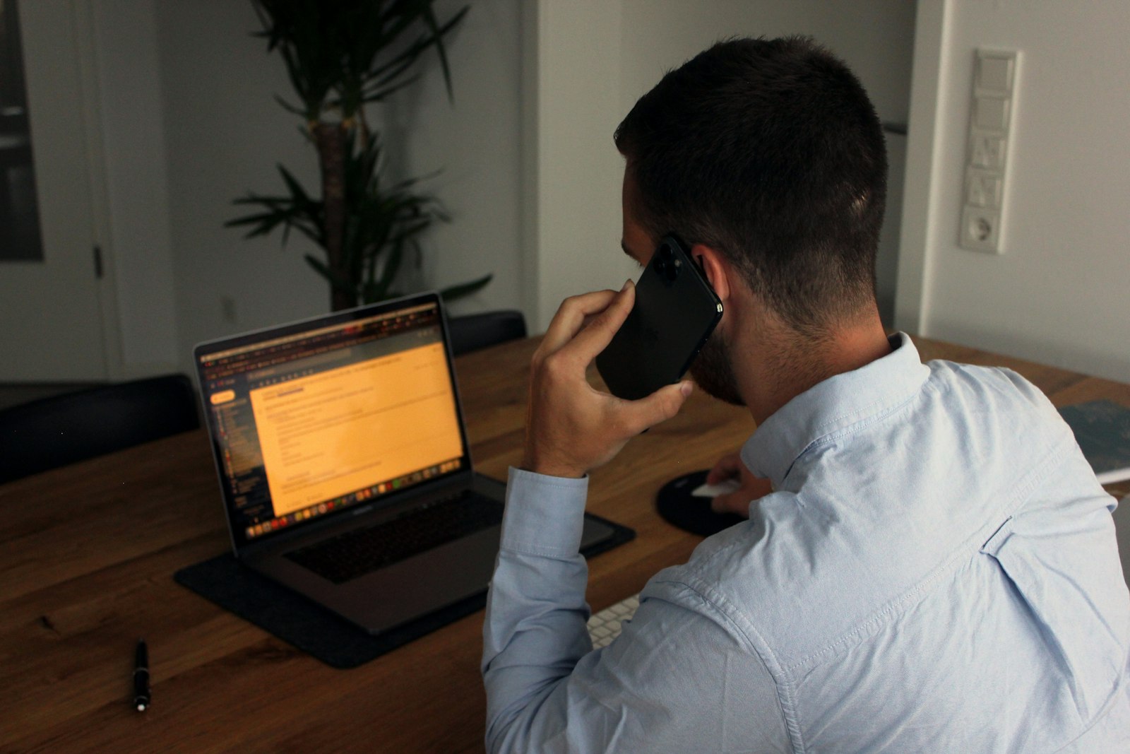 a man in a blue dress shirt holding a black smartphone