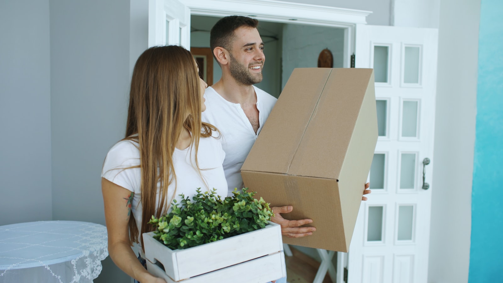 couple carrying moving boxes into a new home